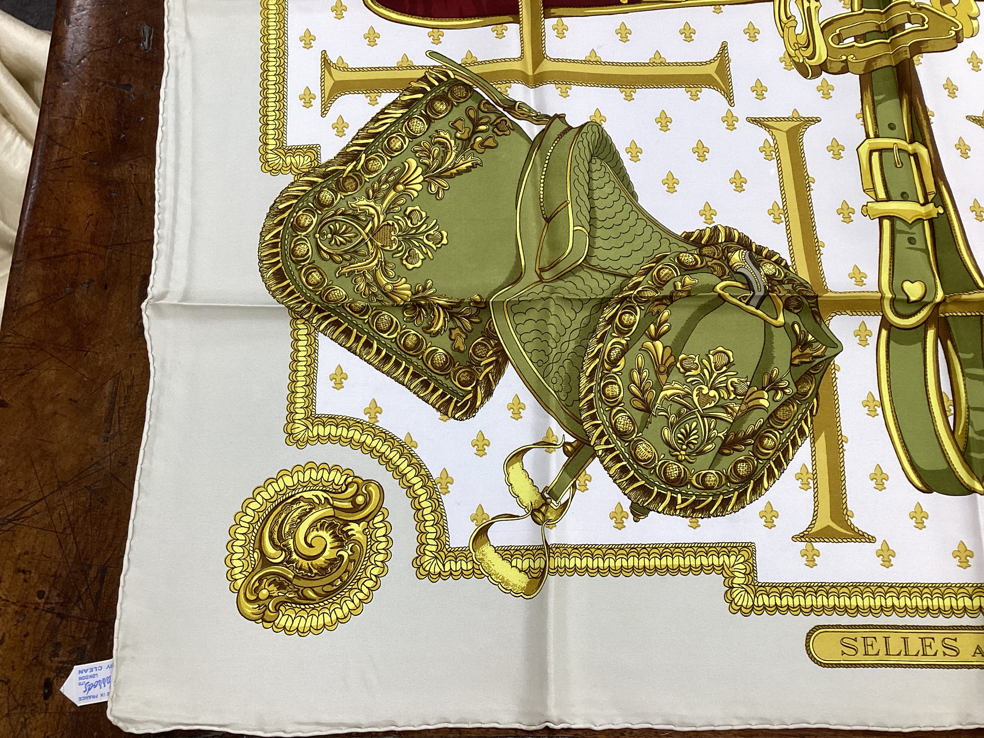 Four vintage Hermes silk scarves including one retailed by Harrods comprising, Selles A Housse, Roues de Canon, Passementerie and a rectangular Brides de Gala example